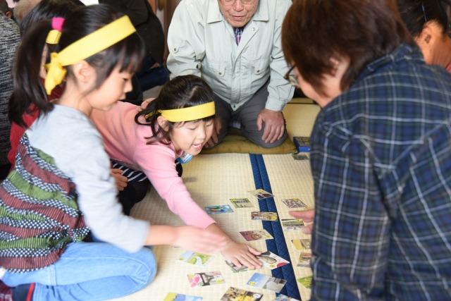 目一杯手を伸ばしてかるたを取ろうとしている女の子の写真