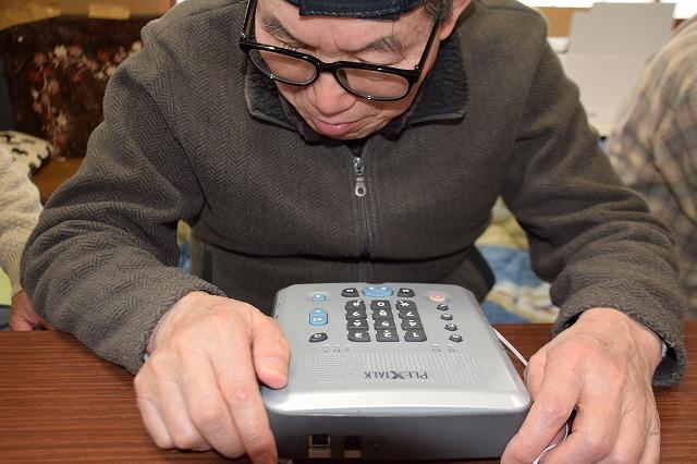 かるたに挑む黄色いはちまきを巻いた子ども達とご老人の方々の写真