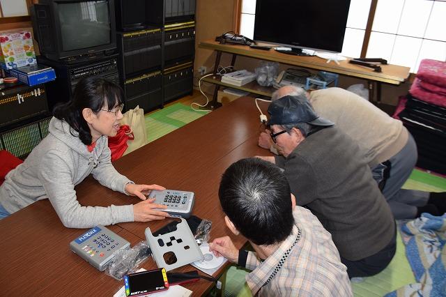 最新式のデイジー再生機を触っている女性参加者とそれを覗き込んでみている男性参加者の写真