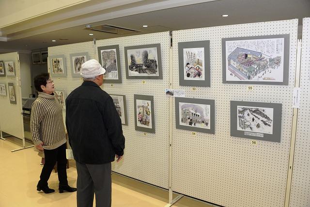 展示されているイラストを鑑賞している男女の様子の写真
