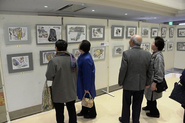 展示されているイラストを鑑賞している男女4人の様子の写真