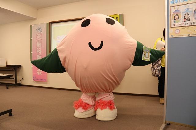 顔がピンクで手が緑色のイメージキャラクターの写真