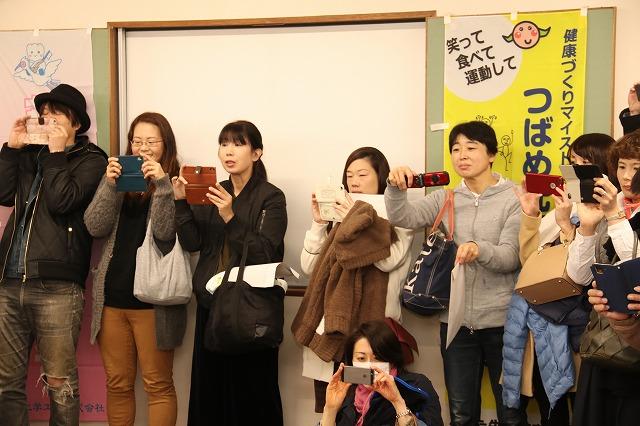 携帯電話を片手に写真に収めようとしている様子の父母の方々の写真