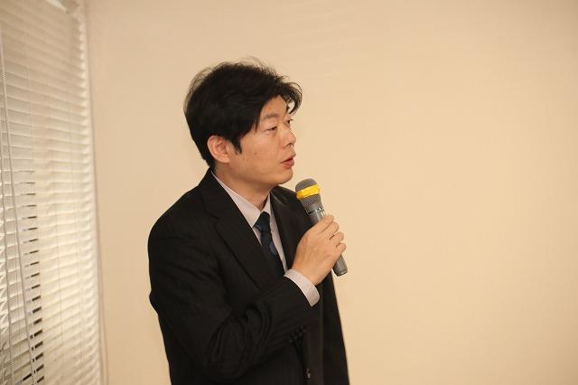 つばめ歯っマイクを持って講演をしているスーツ姿の男性の写真ぴーフェア2017
