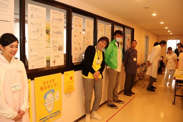 窓に貼られた掲示物を前に説明をしている4人のスタッフの写真