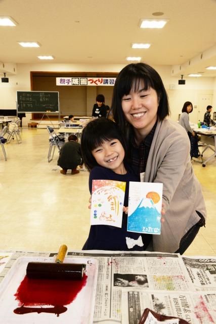 出来上がったハガキサイズの作品を持ち、笑顔の女の子と女性の写真