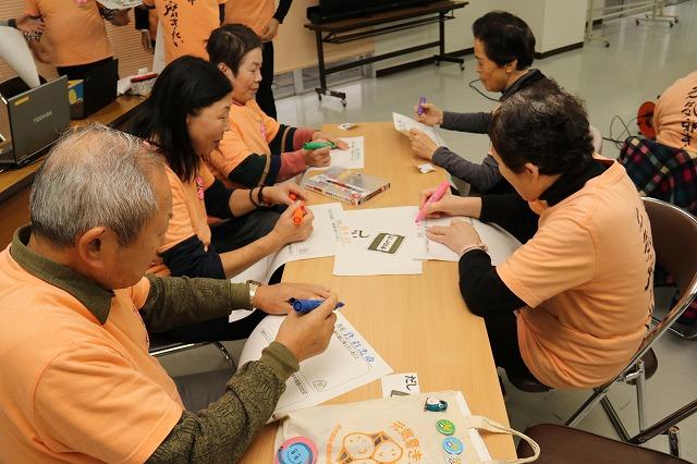 細長いテーブルを囲み、用紙に色付きのペンで書き込んでいる参加者の方々の写真