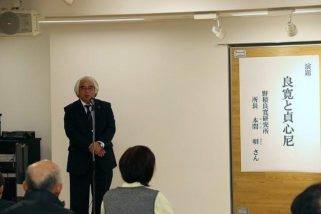 演題「良寛と貞心尼」と書かれた横で、マイクを前に立つ白髪黒縁メガネの男性の写真