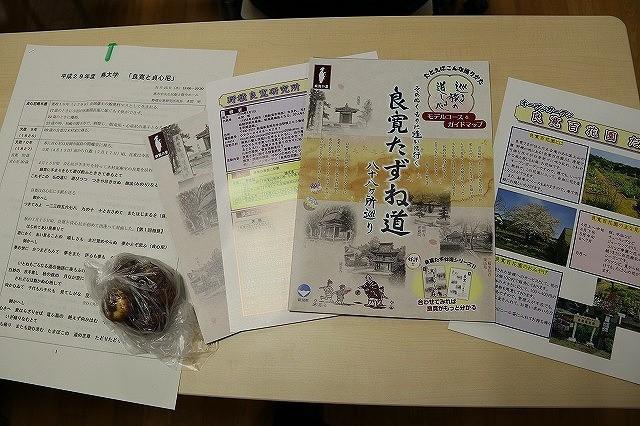 机の並べられた「平成29年度 燕大学 良寛と貞心尼」と書かれたプリントや、「良寛」、「貞心尼」関連のパンフレットとグラジオラスの球根の写真