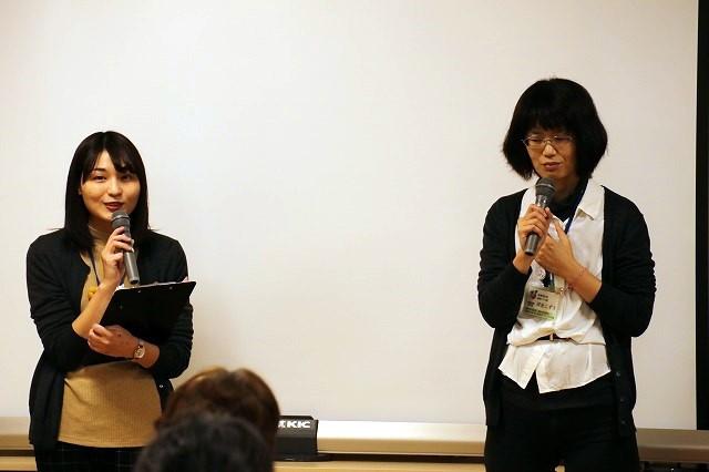 ホワイトボードの前で、マイクとバインダーを持ち話をしている女性と、マイクを手に持っている女性の写真
