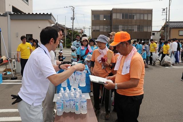 ゴールした参加者たちがスタッフからペットボトルに入った水をもらっている様子の写真