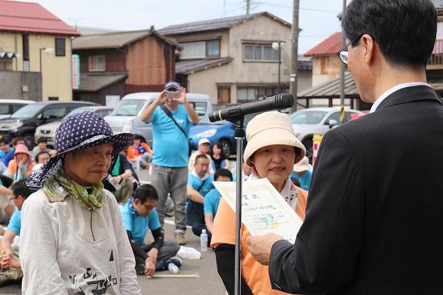 優勝したオレンジチームの代表者2人に賞状が読み上げられている様子の写真