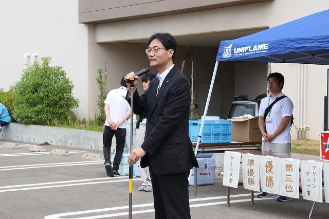 スタンドマイクを握って挨拶をしているスーツ姿の市長の様子の写真