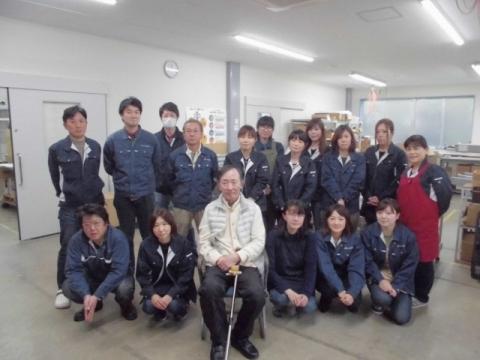 白い服の男性を囲むように並ぶ人々の写真