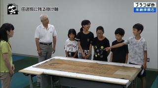 掛け軸を指さして話す児童の写真