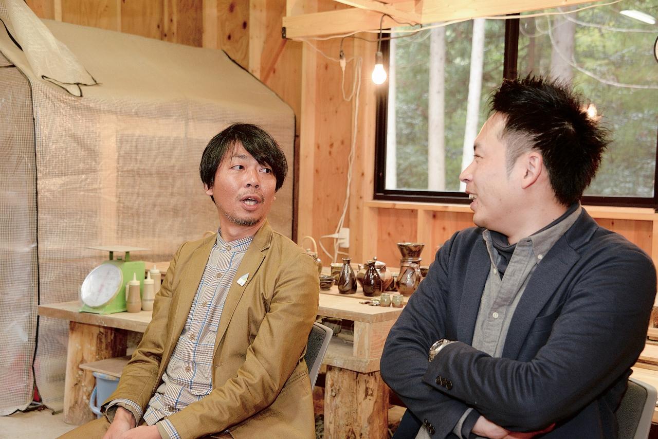 陶芸品が並ぶ工房内で話し合う蓮沼さんと沼田さんの写真
