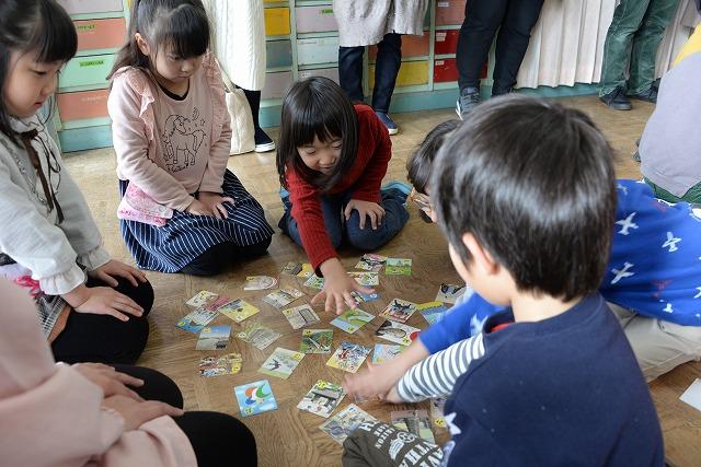 子どもたちが正座をしてかるたに手を伸ばす子どもたちの写真
