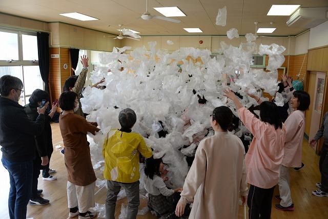 大量のビニール袋で遊ぶ子どもたちを囲んでいる保護者たち様子の写真