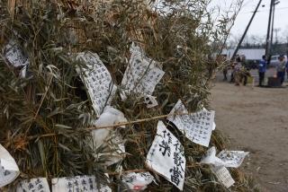 「塞の神」に書き初めの書き損じの半紙が埋められた写真