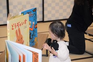 大きな絵本を見つめる子供の写真
