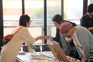 商品を見る客と手渡しする店員の写真