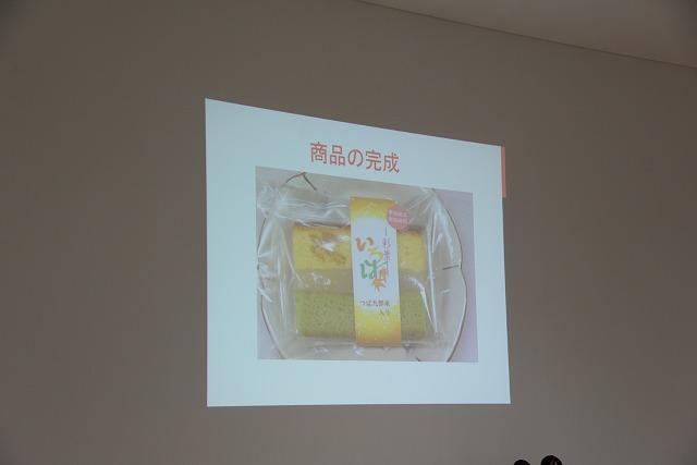 白い壁にプロジェクターで映し出された、「商品の完成」の文字が添えられたお菓子の画像の写真