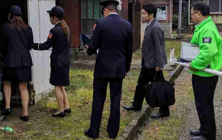 制服を着た職員たちが高齢者の家を訪問している写真