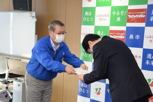 青いジャンパーを着た男性から目録を受け取り深く頭を下げている市長の写真