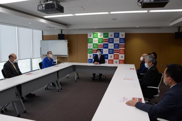 白いテーブルを四角に並べて着席し、会議をする役員男性たちの写真
