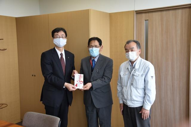 紅白の「のし袋」をカメラに向かって見せる市長と男性の写真