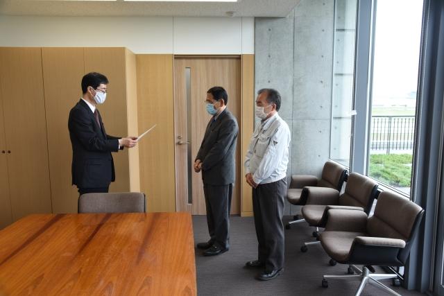 大きな窓のある会議室で市長がお礼状を読み上げている写真