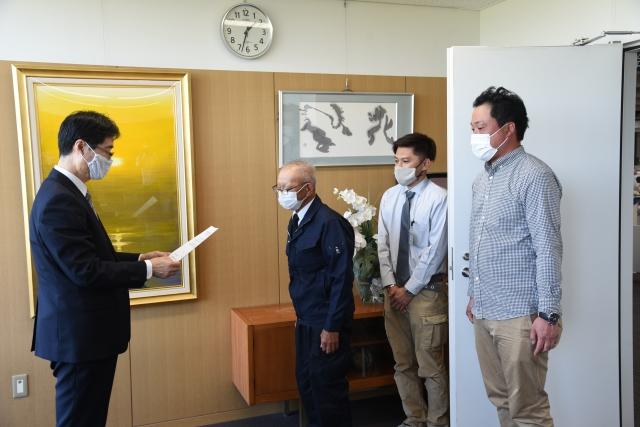 男性と向かい合って、市長が紙に書かれた言葉を読み上げている写真