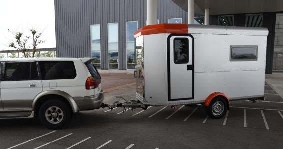 駐車スペースから、車が、トレーラーを牽引して走っていく写真