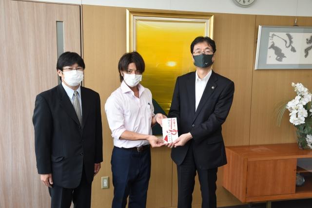 紅白の封筒を手渡している若い男性と、受け取っている市長の写真