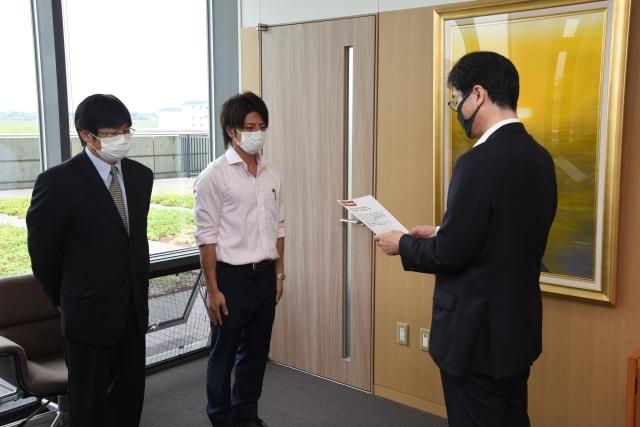 お礼状を読み上げている市長と、並んで聞いている二人の男性の写真