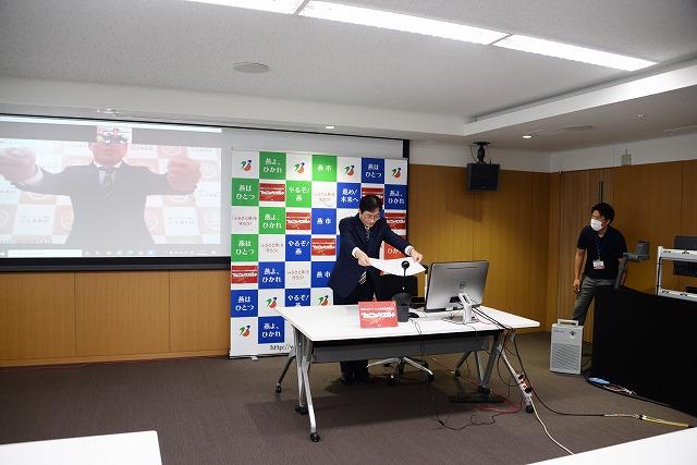 感謝状をパソコンに向かって差し出している市長と、スクリーンの中で受け取る動作をしている男性の写真