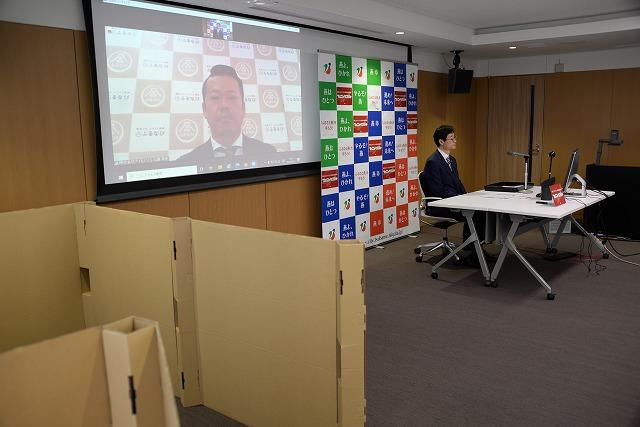 男性の写っているスクリーンの隣で、燕市のボードを前に座っている市長の写真
