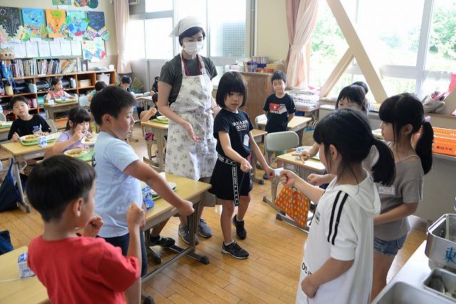 光差し込む教室の中で輪になってじゃんけんで勝負する男女の子供たちの写真