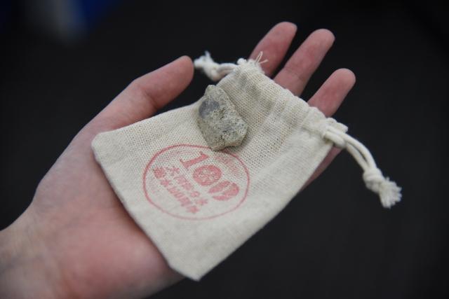 手の平にのせられたガチャガチャ景品である通水石とそれを包む麻袋の写真