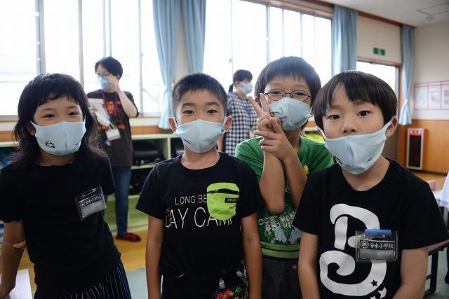 配られたマスクを付けて横に並ぶ4人の男女の子供達の写真
