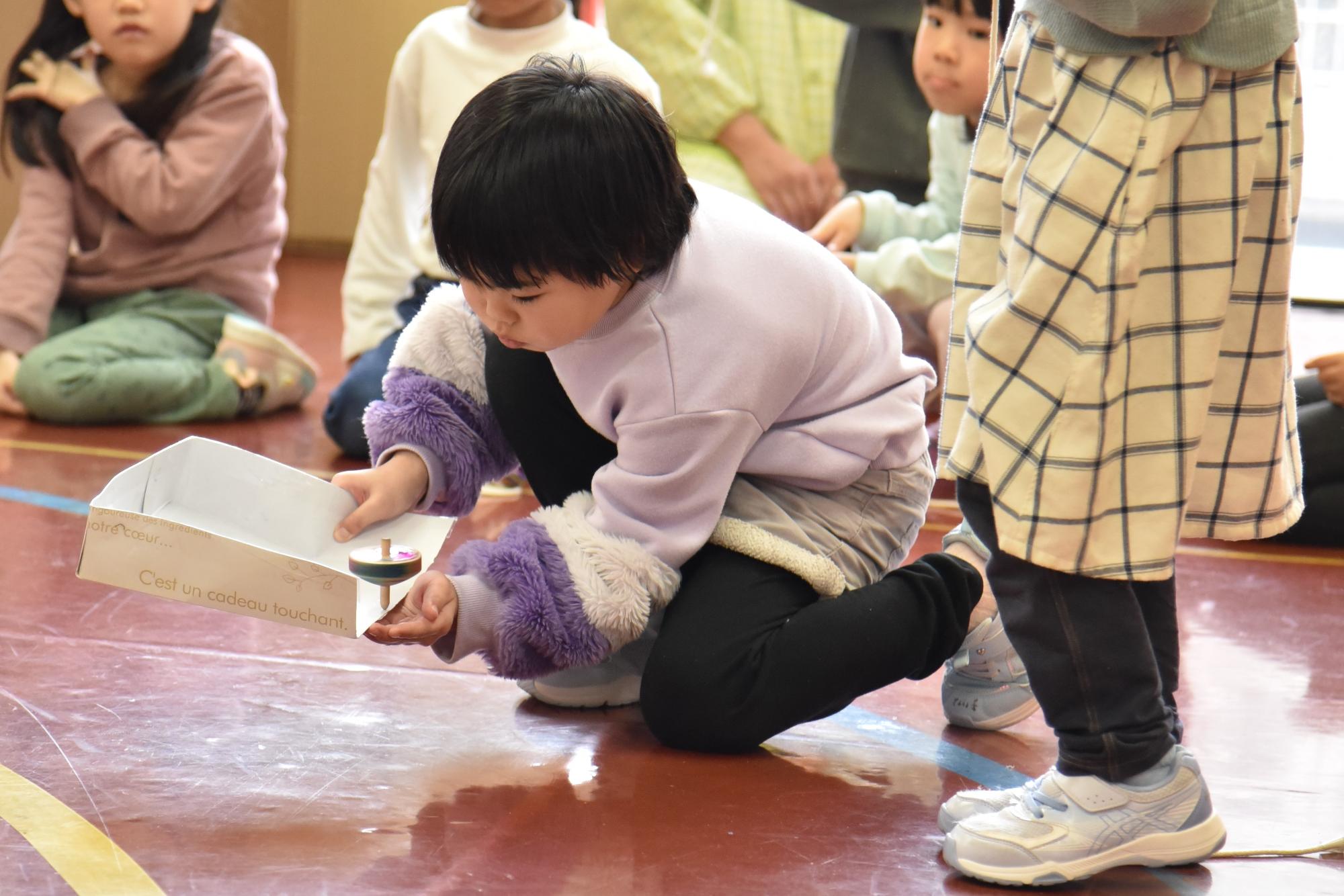 手の上でこまを回そうとする子ども