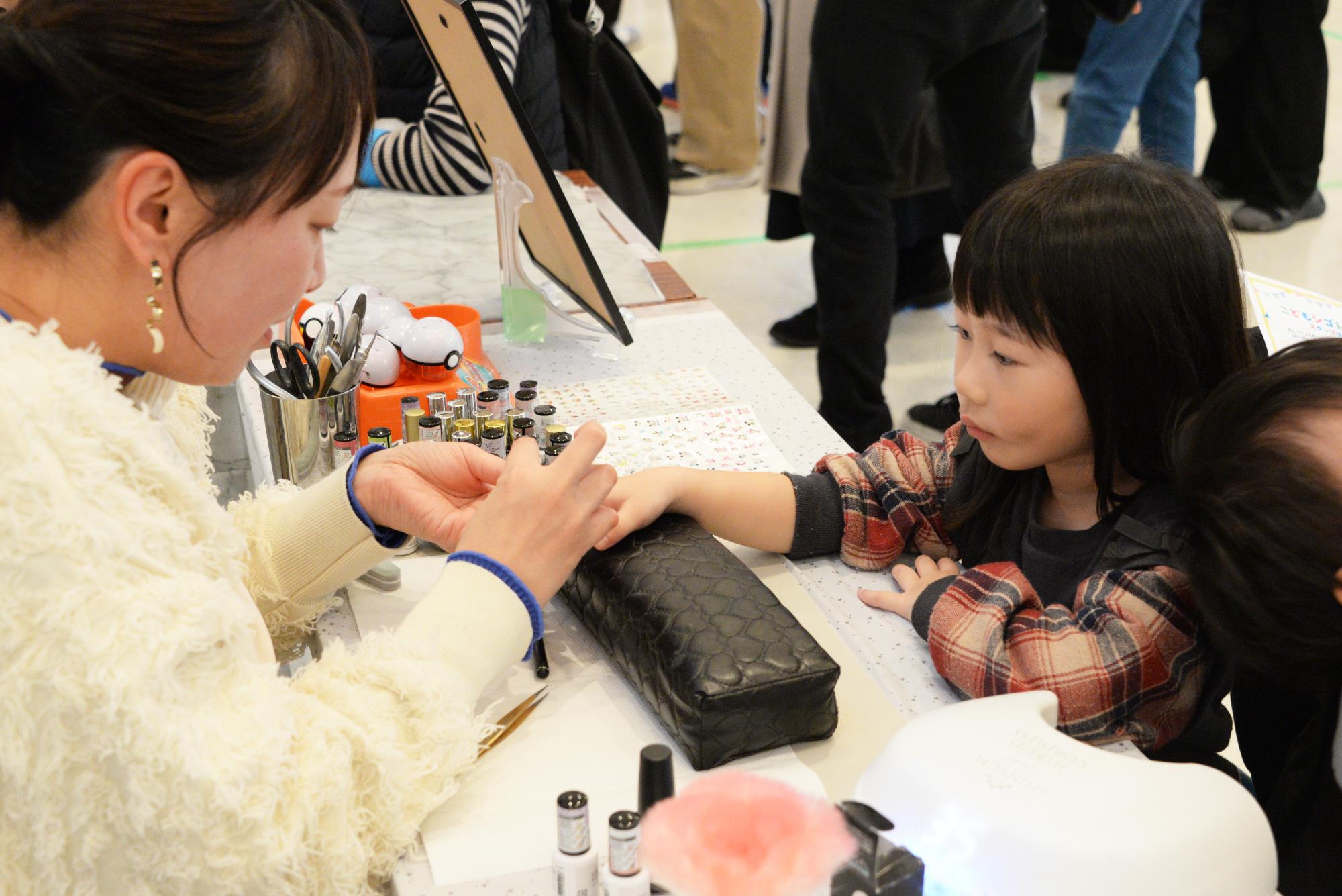 ネイルの体験をする子どもとネイルをするネイリスト
