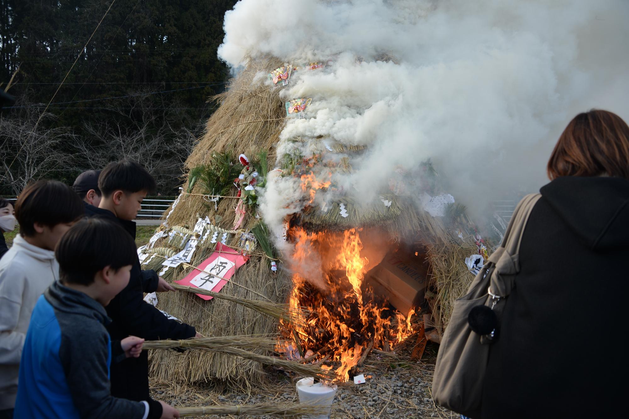塞の神に藁を納める子どもたち