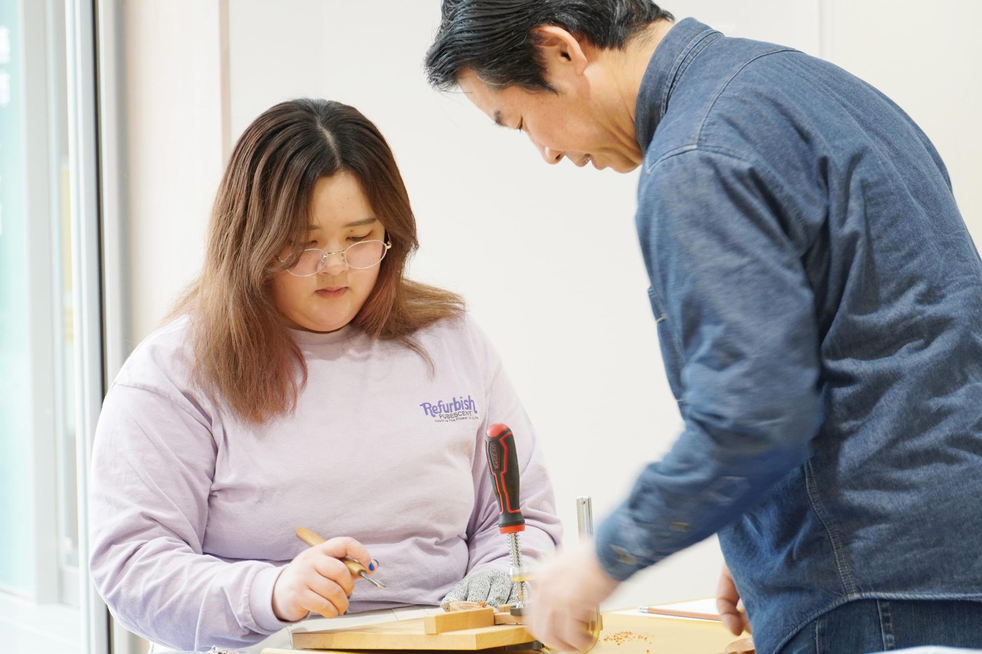 スプーンの彫り方を教わっている様子