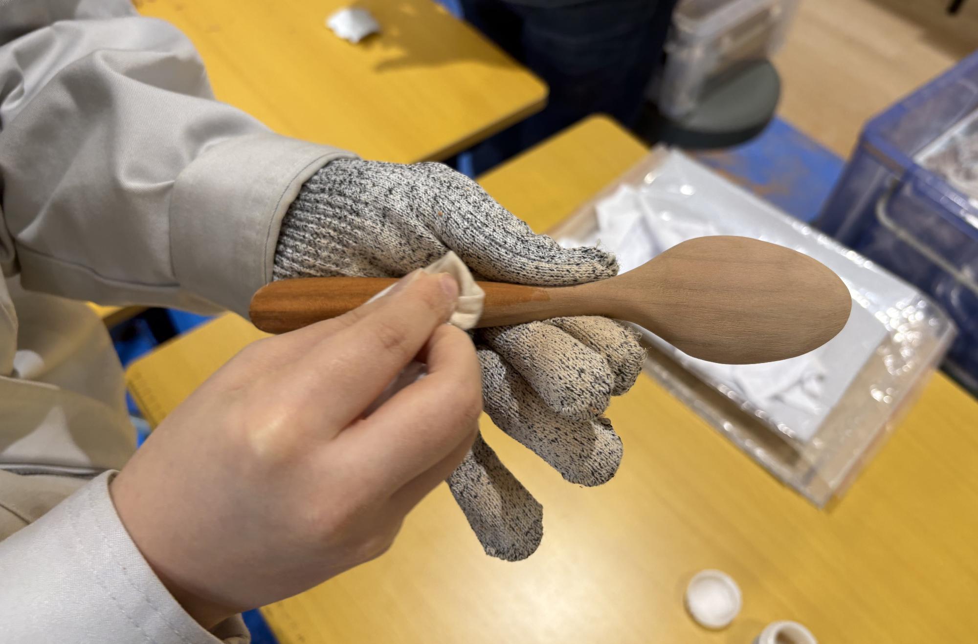 木彫りスプーンを仕上げ材でコーティングしている様子