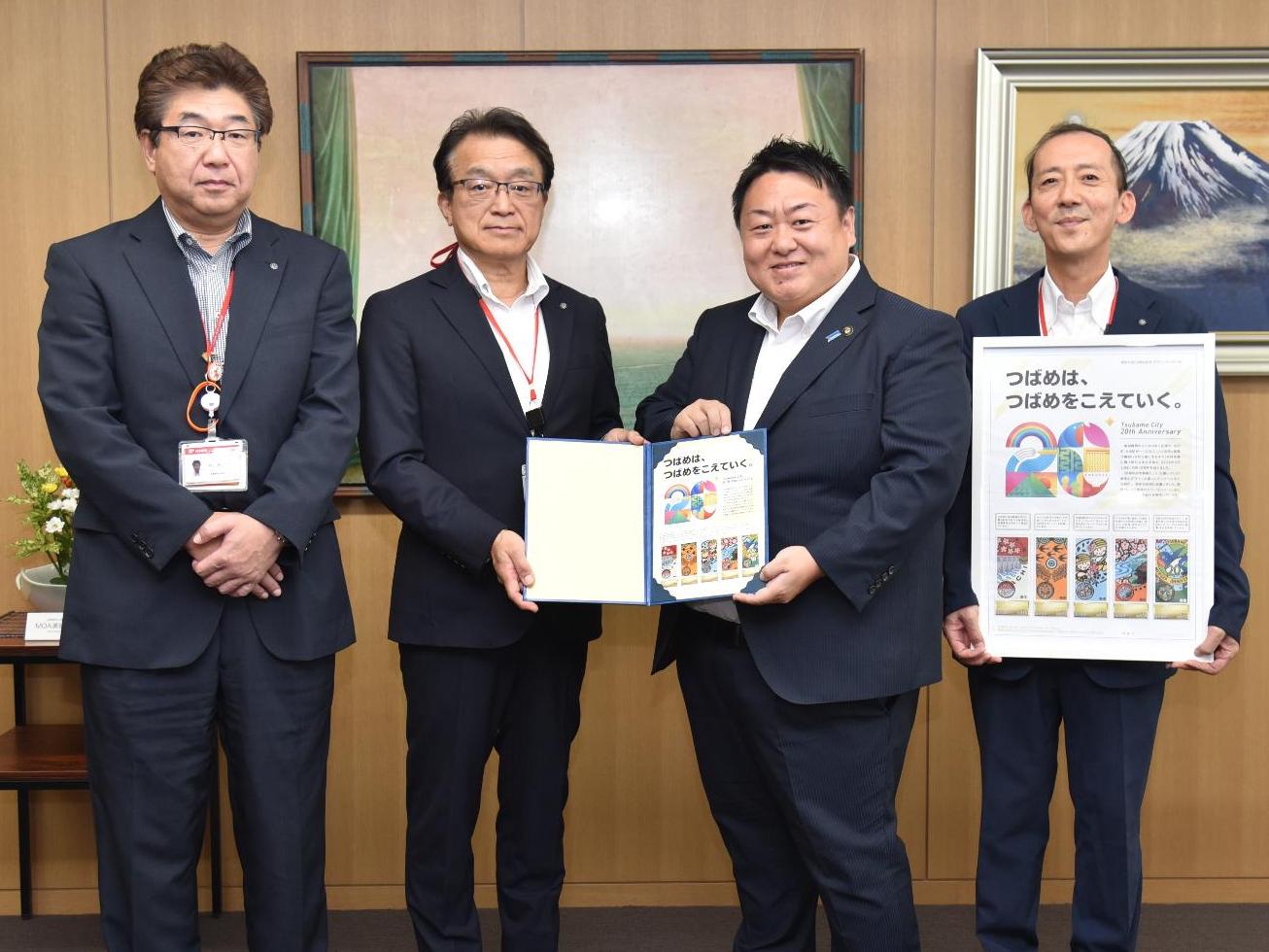 贈呈された切手を持つ佐野市長と日本郵便の3人