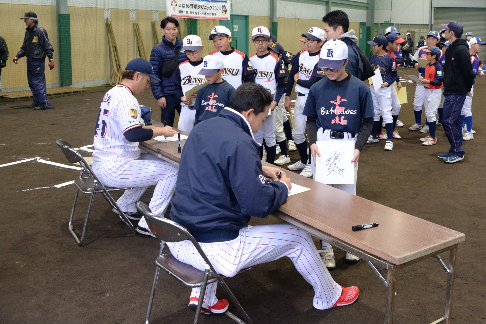 サインをする星選手と小澤選手