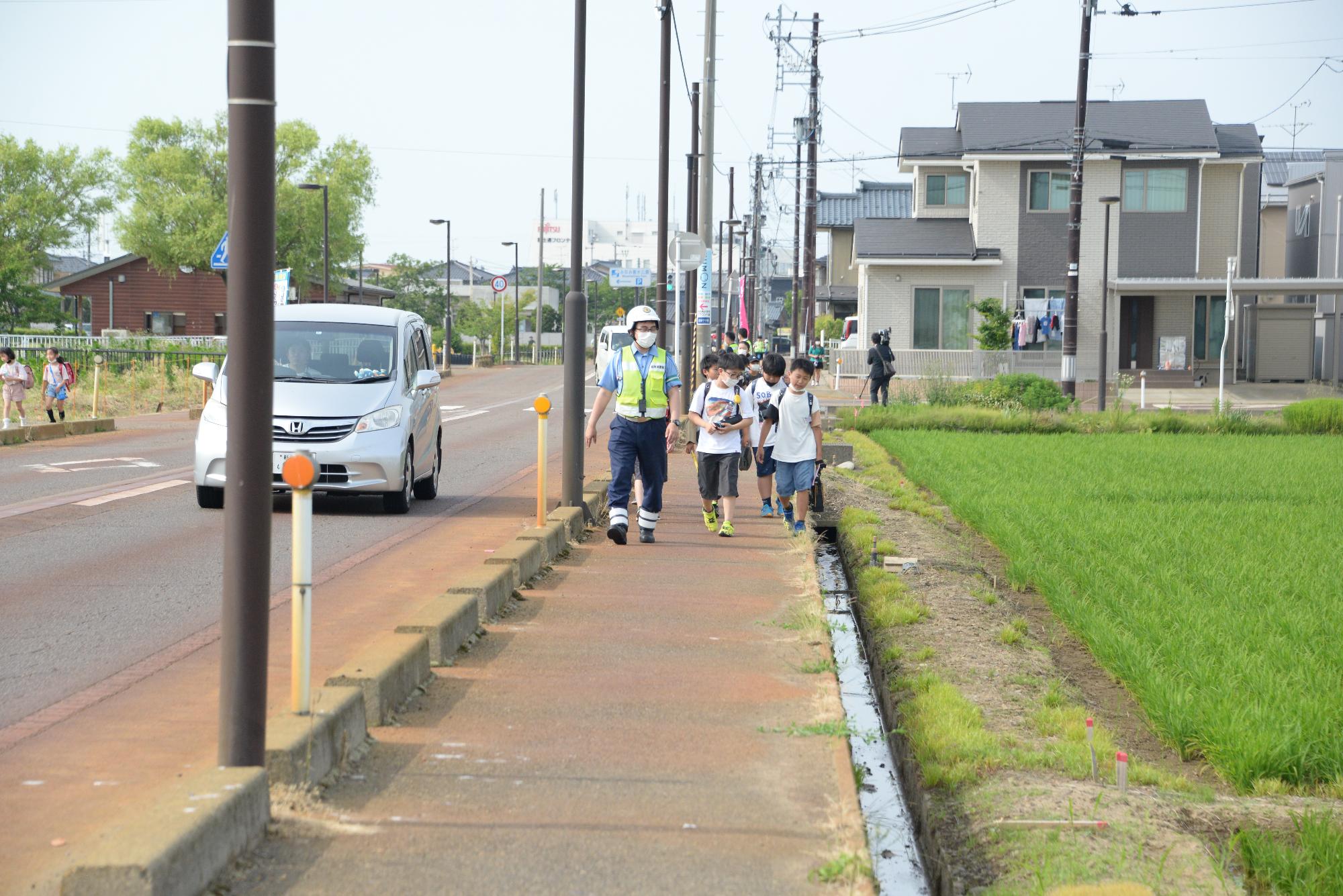 警察官と一緒に下校する子どもたちの列