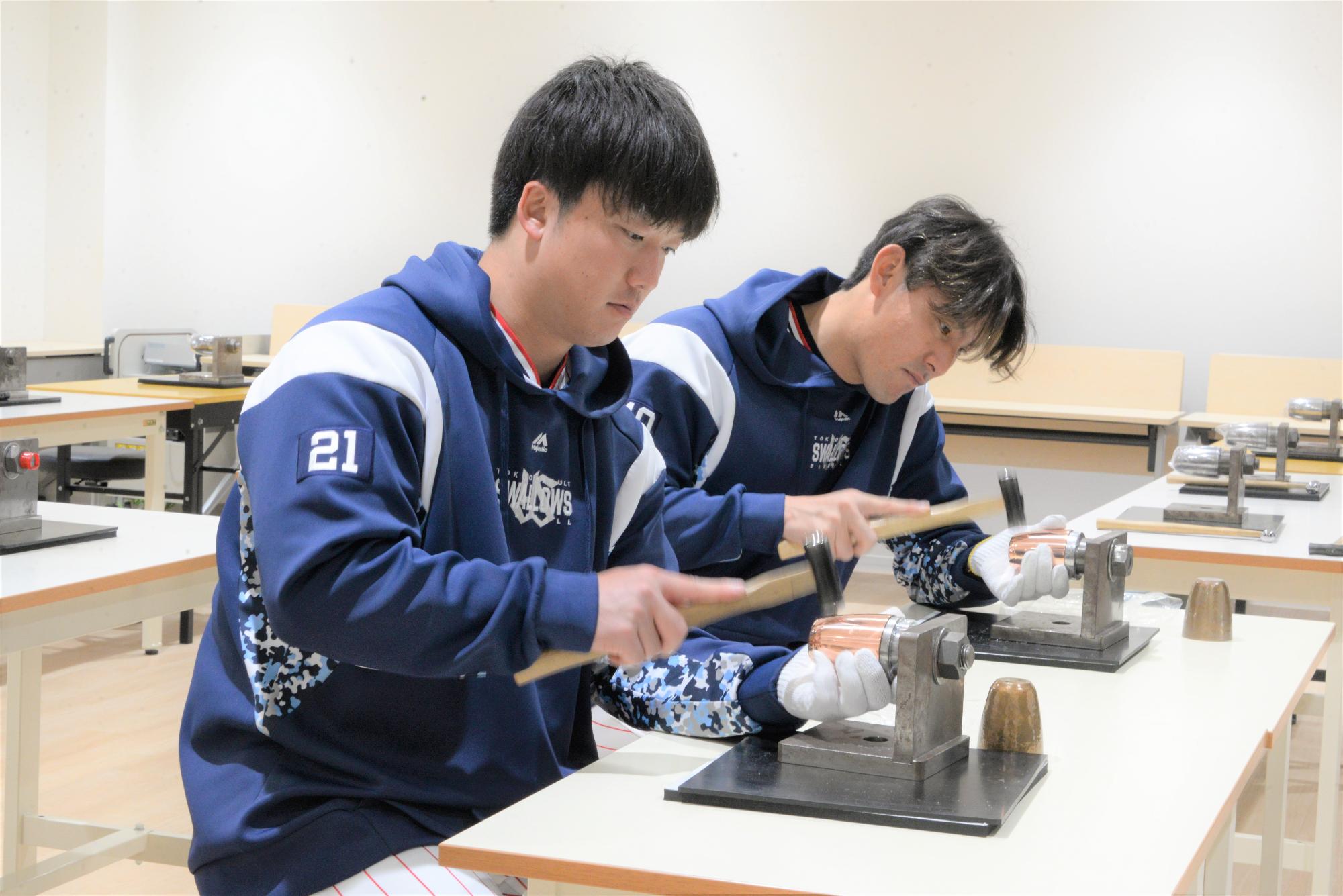 鎚目入れ体験をする吉村投手と高梨投手の写真