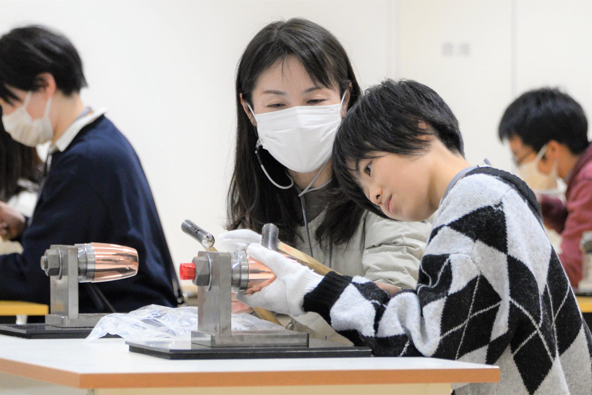 鎚目入れ体験をする親子の写真